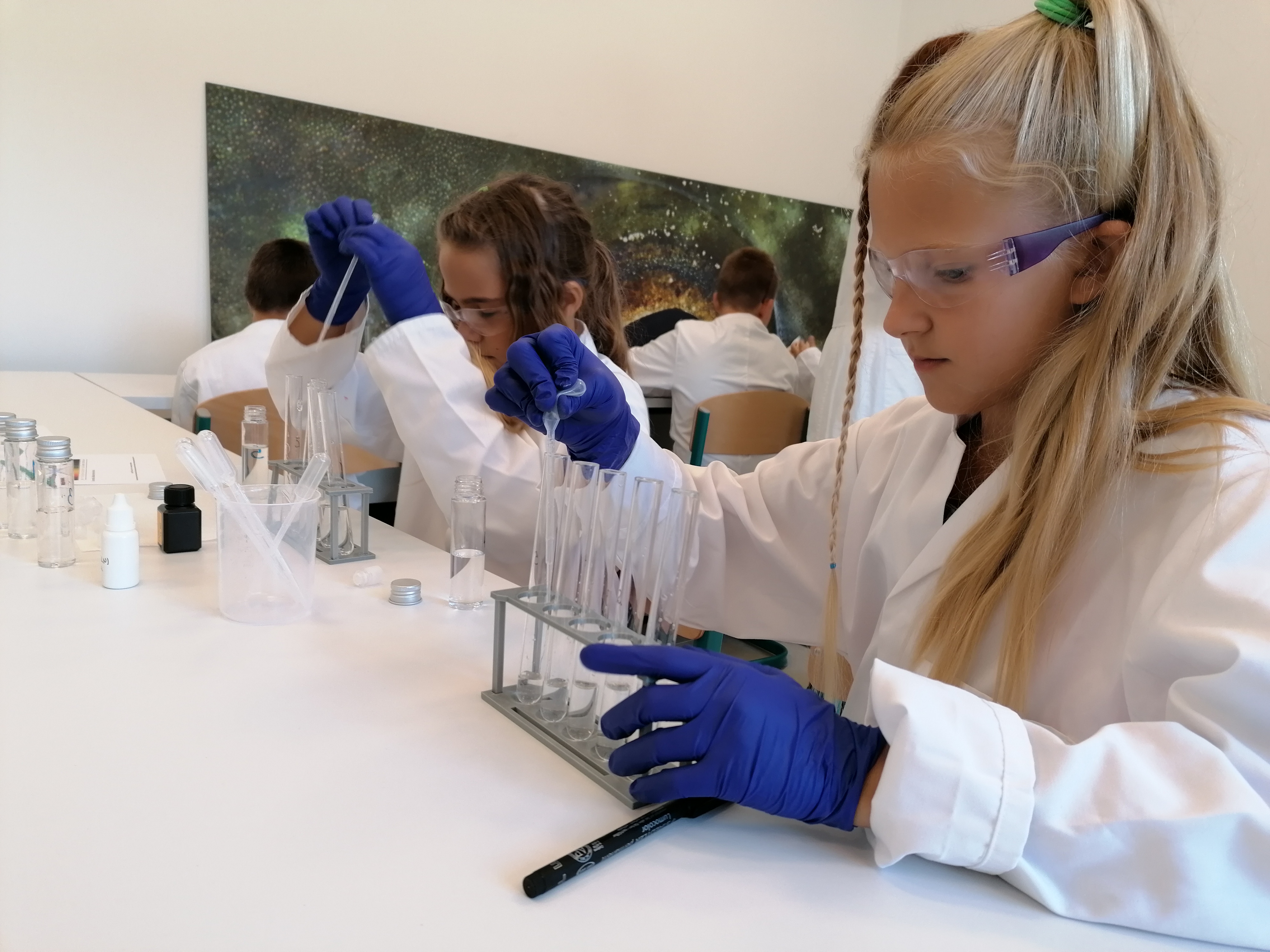 Child in a lab coat working with test tubes during a hands-on science activity